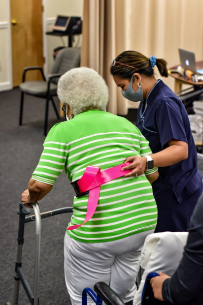 Female physical therapist assists elderly woman with walker